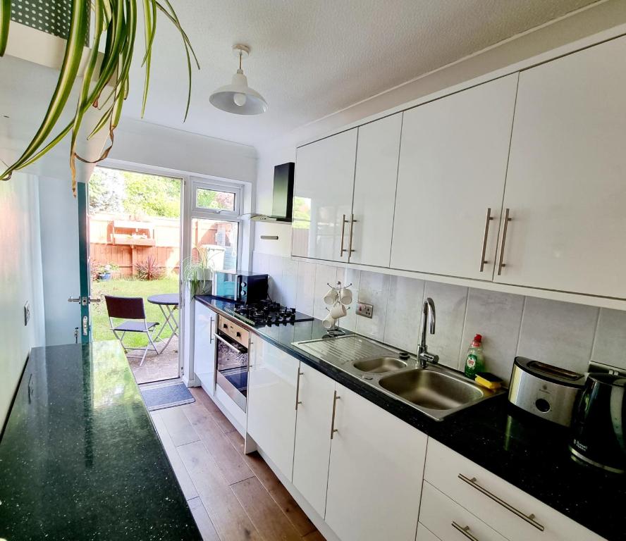 a kitchen with white cabinets and a sink at Private one bedroom apartment with garden and parking in Thame