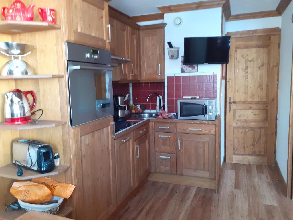 een keuken met houten kasten, een wastafel en een magnetron bij Appartement exceptionnel à Valmorel in Valmorel