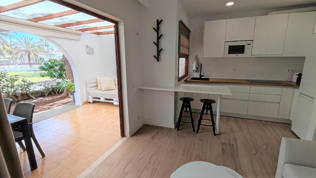 a kitchen with a counter and stools in a room at Excelente Bungalow en Maspalomas in San Bartolomé de Tirajana