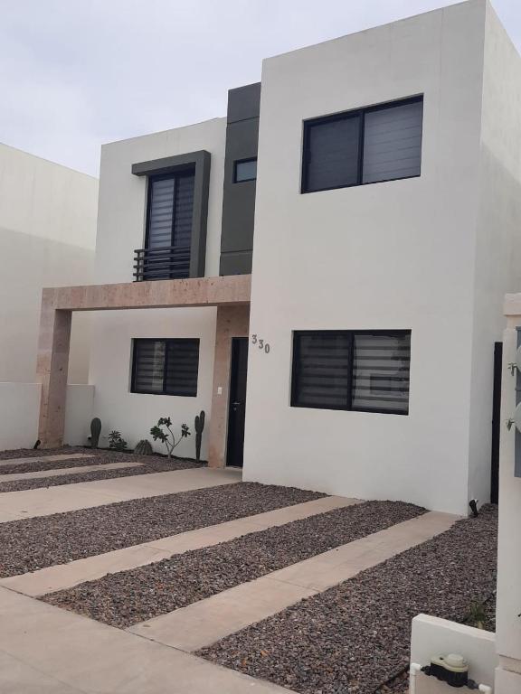 une maison blanche avec des fenêtres à volets noirs dans l'établissement Beautiful new house with pool club, à Los Bledales