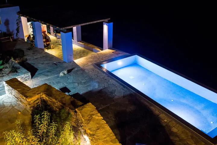 a large swimming pool in a house at night at Loukoum Syros Cyclades in Rózia