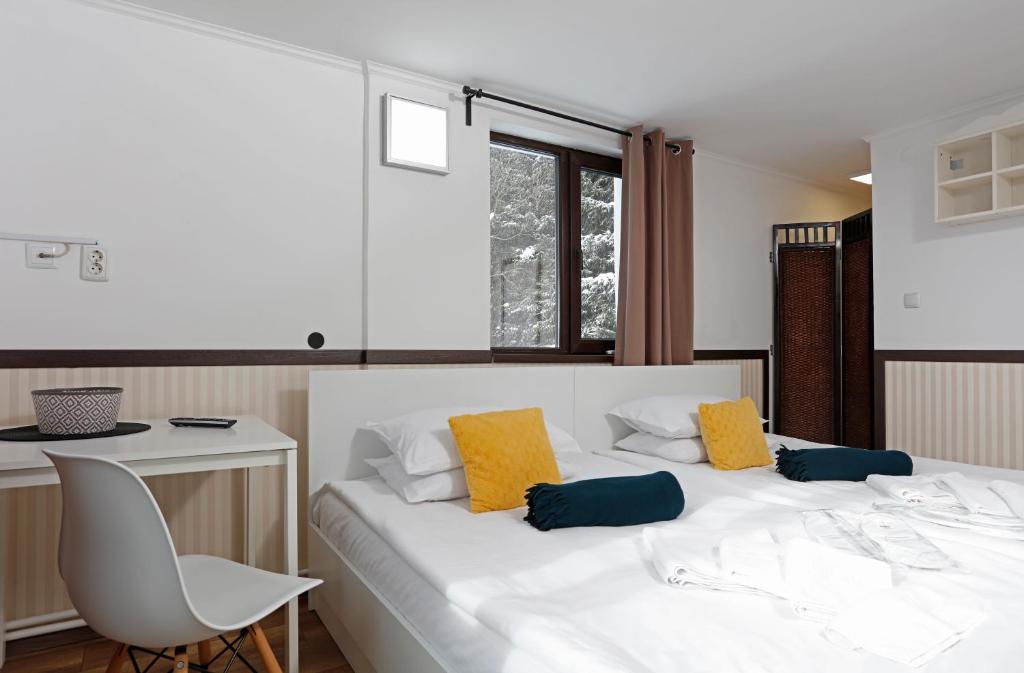 a bedroom with a white bed with yellow and blue pillows at Caraiman Hive in Buşteni
