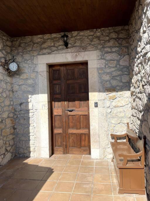 uma porta de madeira num edifício de pedra com um banco em La Llamera em Ortiguero