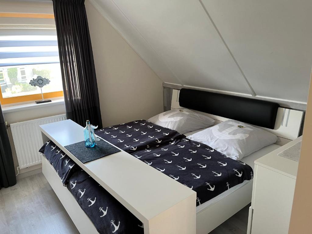 a small bed with a black and white comforter at Perle am Ijsselmeer mit eigenem Tretboot in Medemblik