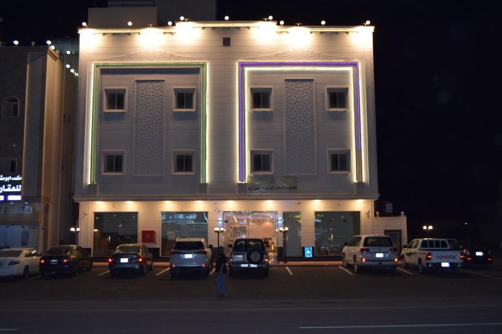 un grand bâtiment avec des voitures garées dans un parking dans l'établissement فندق اللؤلؤة الذهبي, à Sīdī Ḩamzah