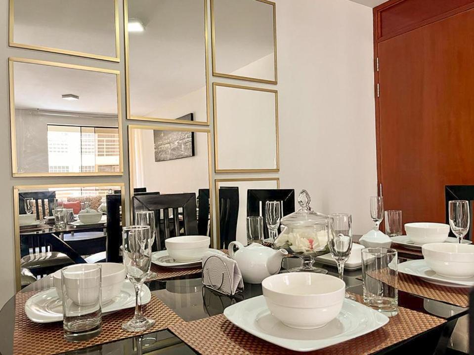 une salle à manger avec une table, des assiettes et des verres dans l'établissement Hermoso Departamento dentro de un Condominio, à Chiclayo