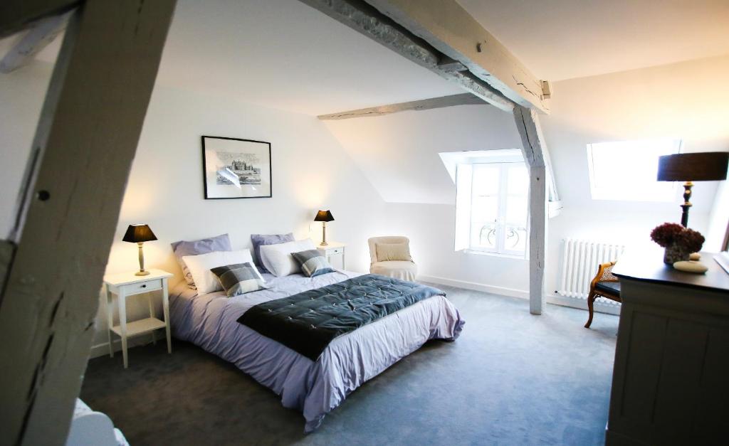 a bedroom with a bed and two chairs and a window at L’Atelier in Saint-Denis-sur-Loire