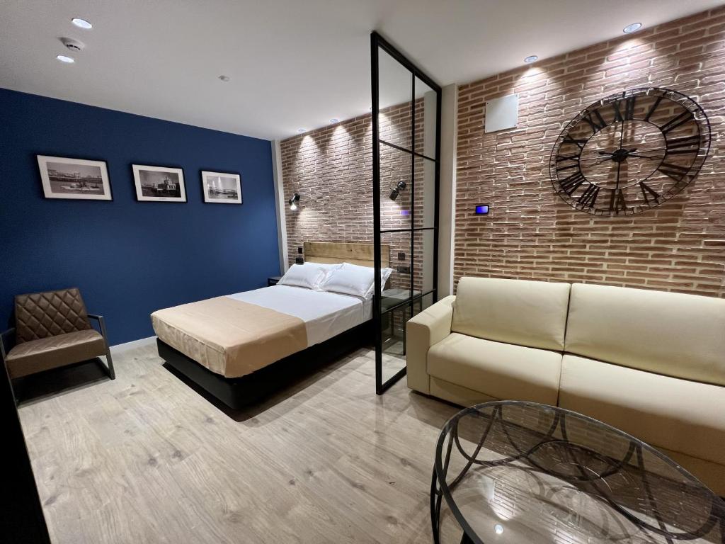 a bedroom with a bed and a clock on a brick wall at Aparthotel Luz de Gades - Suites Spa Gym - Adults Only in Cádiz
