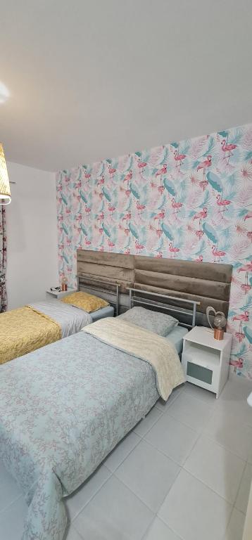 een slaapkamer met 2 bedden en een muur met behang bij MAYA in Paphos City