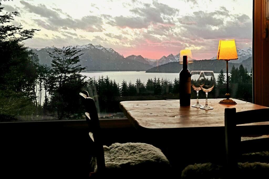 une table avec une bouteille de vin et deux verres dans l'établissement Puerto Esmeralda ESPECTACULAR DEPTO CON VISTA AL LAGO NAHUEL HUAPI, à Villa La Angostura