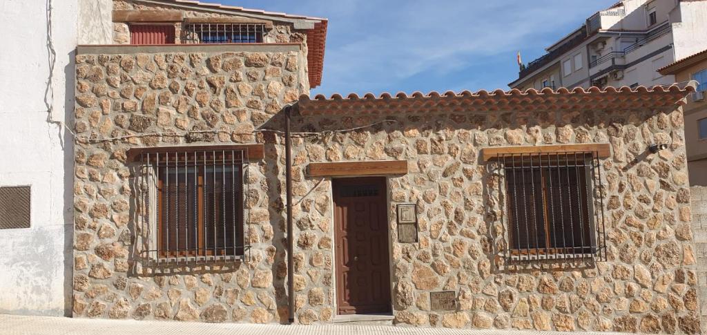 een stenen gebouw met een deur en twee ramen bij Casa Rural Ramblizo in Elche de la Sierra