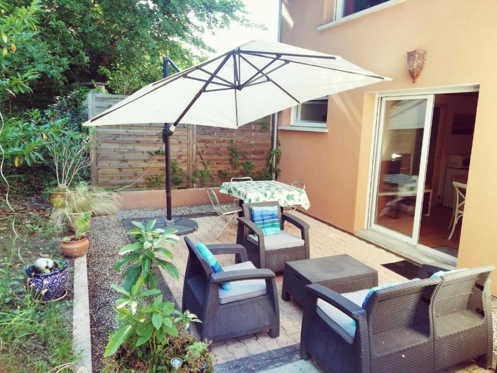 a patio with a table and chairs and an umbrella at Gîte 4 personnes vue sur les pins proche de la Dune du Pilat, entre lac, Bassin et plages océanes in La Teste-de-Buch