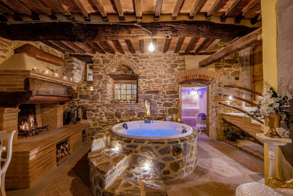 a large bathroom with a large tub in a stone wall at San Lazzo Luxury Room - ROOM & PERSONAL SPA in Castiglion Fiorentino