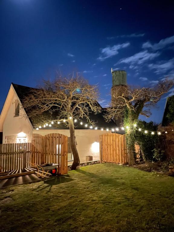 una casa con una valla y un árbol con luces en Lilla Villan en Höganäs