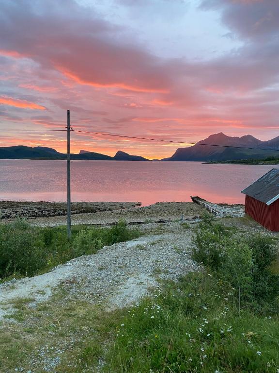 a sunset over a body of water with a pole at Charming holiday home in Tromsø