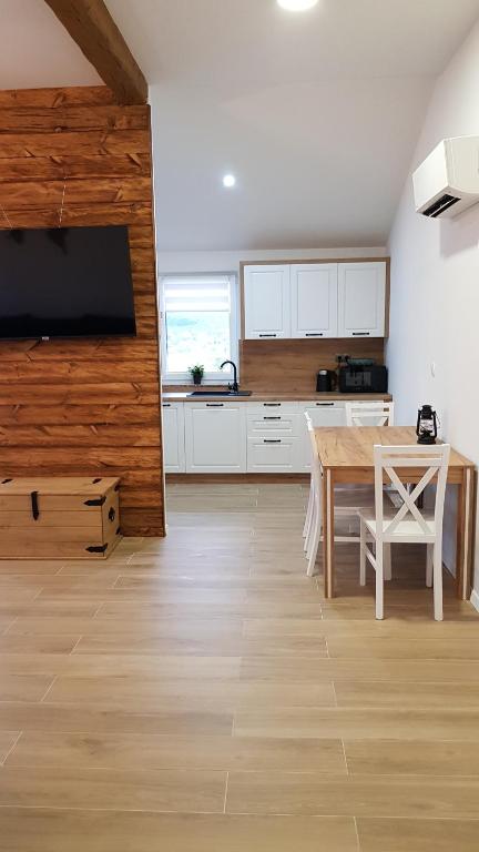 a kitchen with white cabinets and a wooden table at Tiki Tita Apartman in Čižići