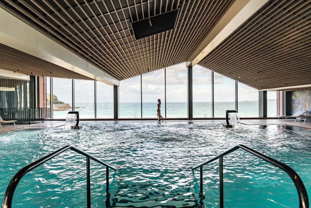 佩羅斯－吉雷克的住宿－Hôtel Roz Marine Thalasso Resort，站在建筑物游泳池中的女人