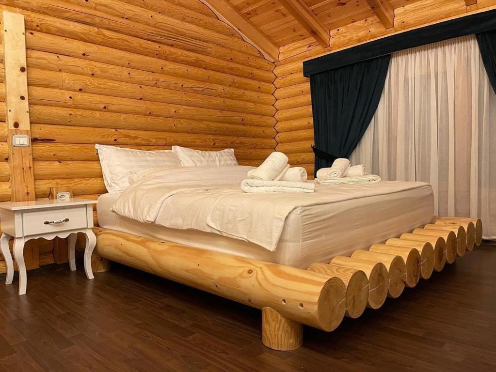 Cama en habitación de madera con pared de madera en Resort Mezini, en Ersekë