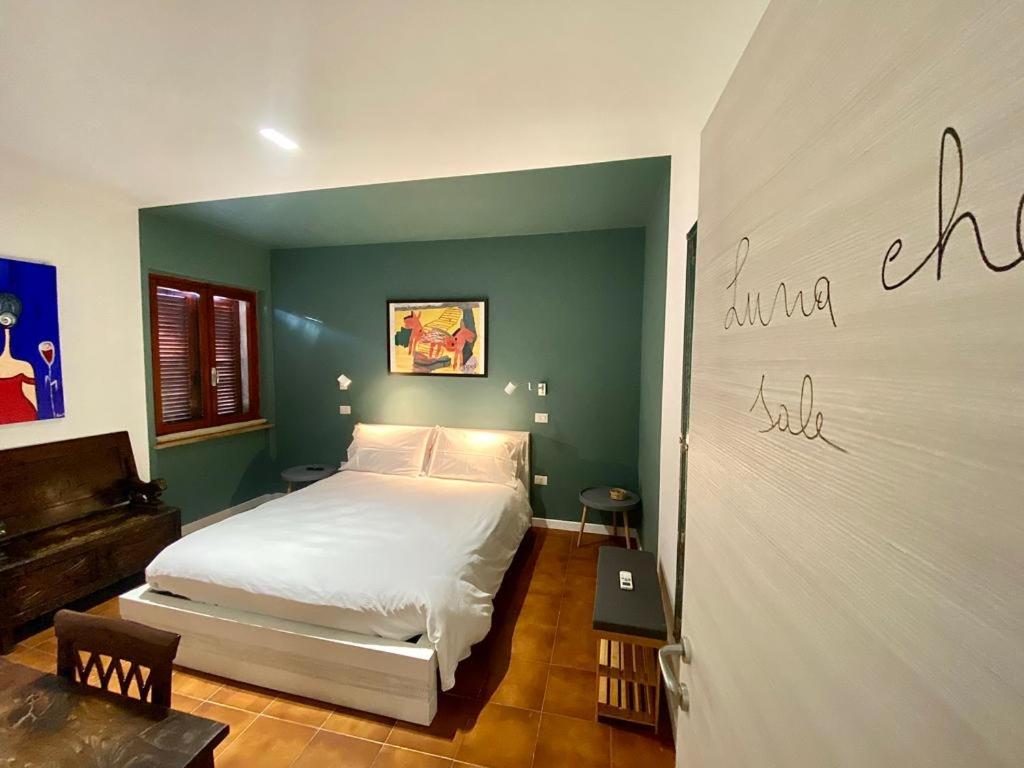 a bedroom with a white bed and a green wall at Da li Poteri in Colfiorito