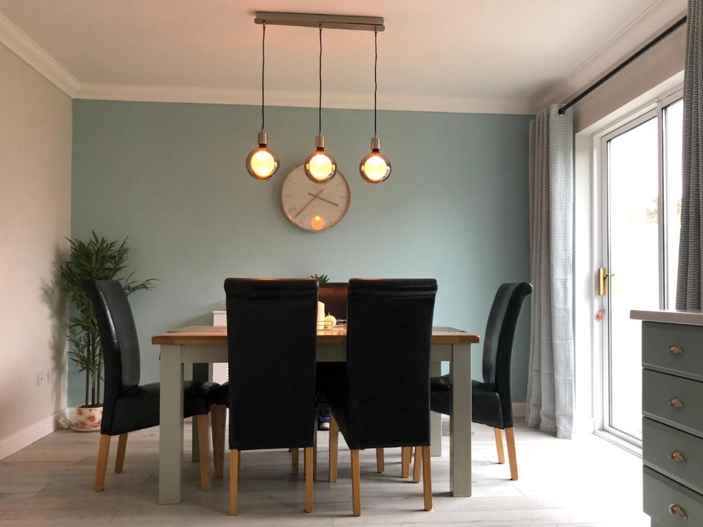 a dining room table with black chairs and a clock at Fraunhill in Swinford