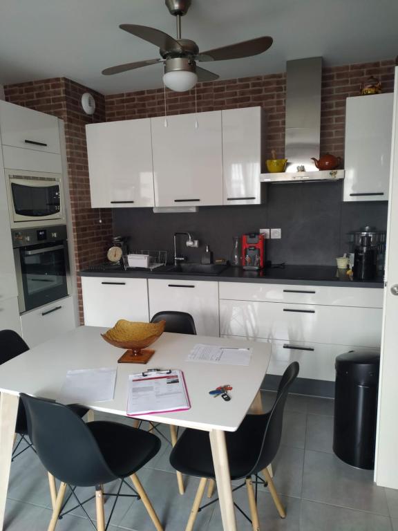 une cuisine avec des armoires blanches et une table avec des chaises dans l'établissement Les Salins à Sète proche plages, à Sète