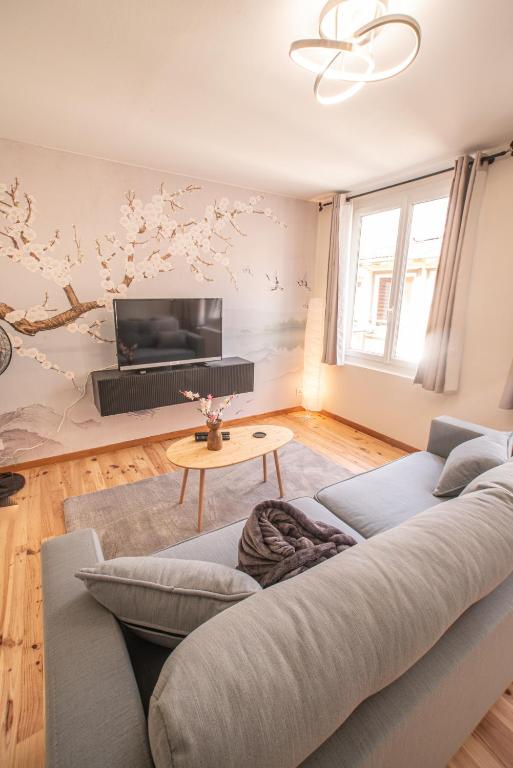 a living room with a couch and a tv at Appartement - Le Mikado - Hyper-centre - Wi-Fi- Espace de travail - Confort in Saint-Étienne