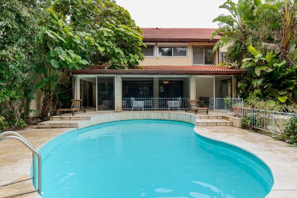 ein Pool vor einem Haus in der Unterkunft Heated Pool! 1 Minute Walk To The Beach! PURA VIDA Villa in Herzlia