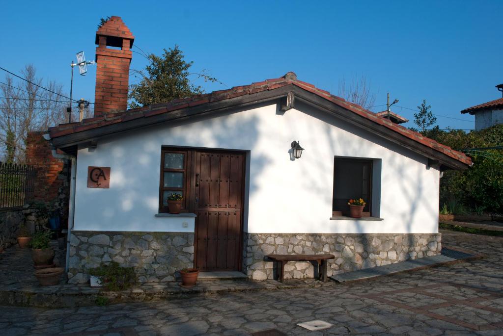 a small white house with a brick chimney and a door at La Casina de la Huerta in Llanes