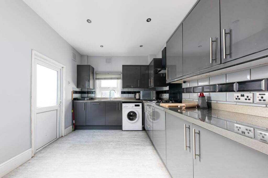 a large kitchen with a washer and dryer in it at Cozy 4 bedroom home in Hackney, London in London