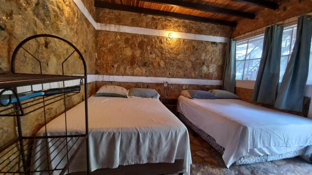 a bedroom with two beds in a brick wall at Hotel Colibrí Petén in Santa Elena