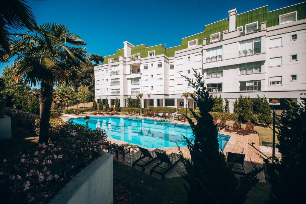 un hotel con piscina di fronte a un edificio di Superitá Campos do Jordão - Apto de alto padrão com estrutura de resort perto do Capivari e Morro do Elefante a Campos do Jordão