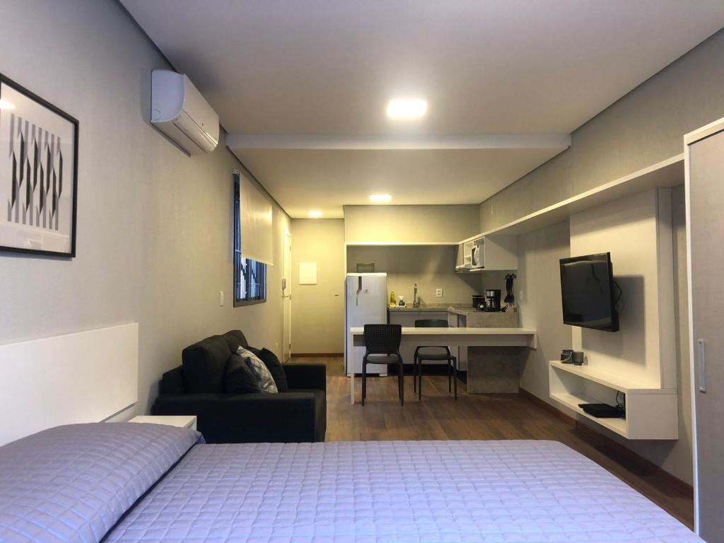 a bedroom with a bed and a couch and a kitchen at Villa Leopoldina - Studios de aluguel por temporada no Moinhos de Vento in Porto Alegre