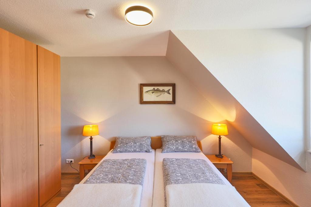 2 Betten in einem kleinen Zimmer mit 2 Lampen in der Unterkunft Ferienwohnung mit Seesicht Grimmershörnbucht in Cuxhaven