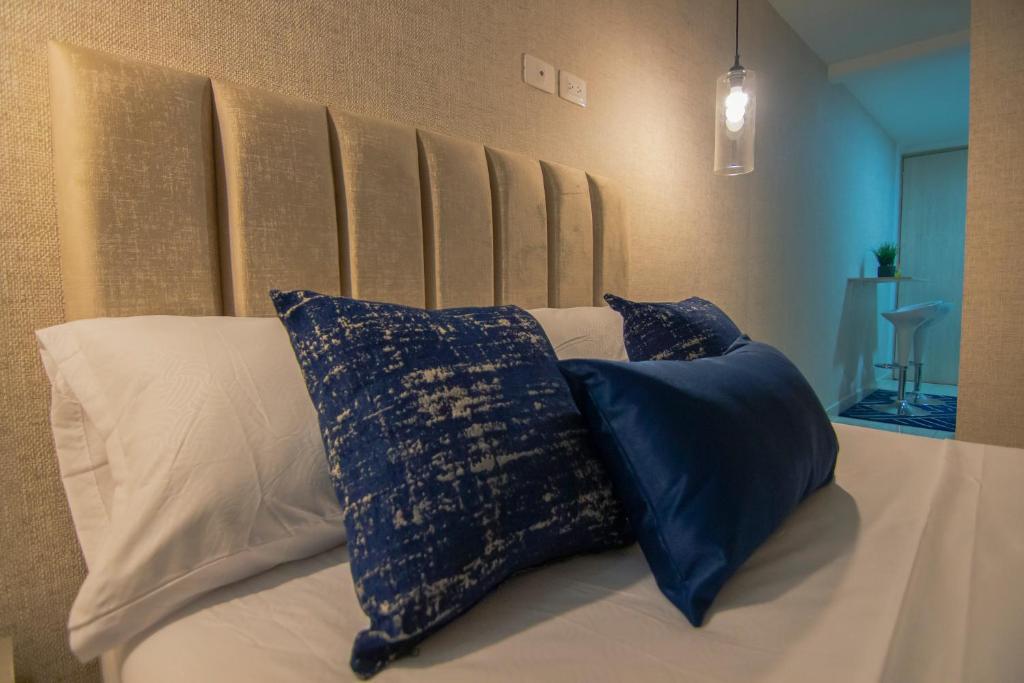 Una cama con almohadas azules y blancas. en Moderno loft en el centro de Pereira, en Pereira