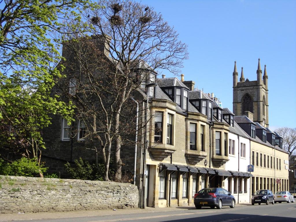 a building on a street with a church in the background at Pentland Hotel in Thurso