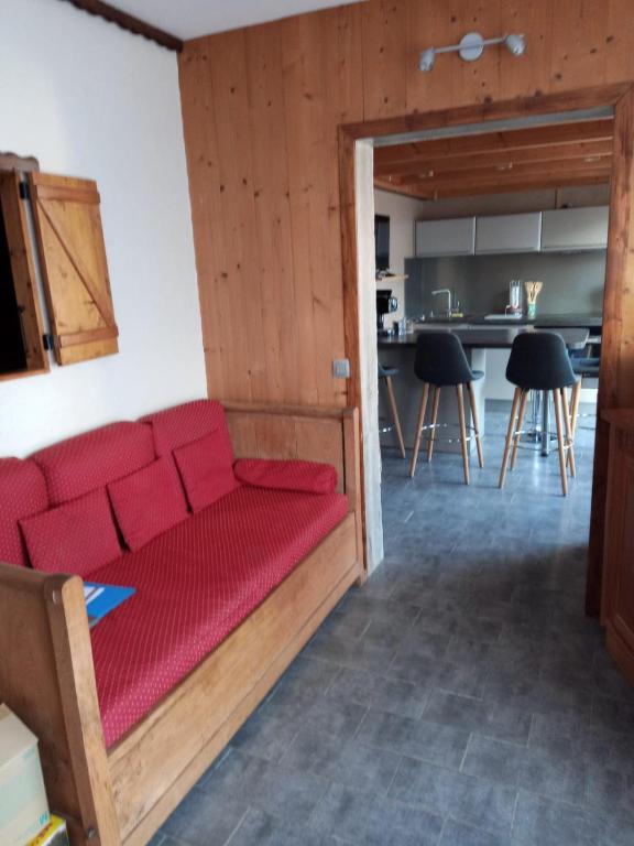 un salon avec un canapé rouge et une cuisine dans l'établissement Appart La Porte des Neiges - Saint Jean de Sixt (La Clusaz, Le Grd Bornand), à Saint-Jean-de-Sixt