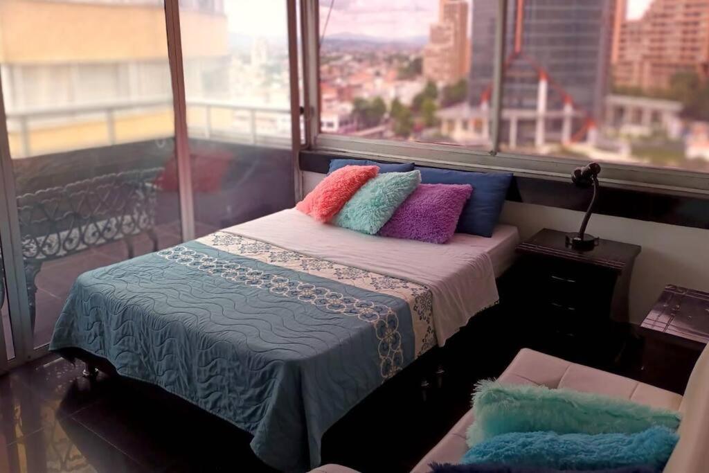 1 cama con almohadas coloridas en una habitación con ventana en Apartamento centro. Espectaculares vistas, en Bogotá