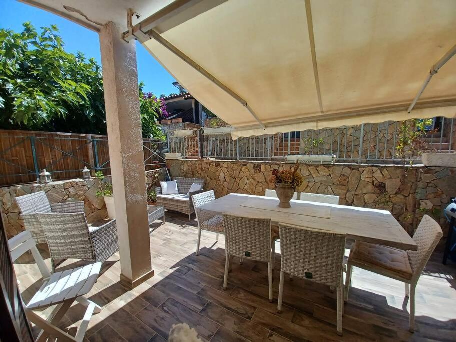 una mesa y sillas bajo una sombrilla en un patio en BAIA DE BAHAS- appartamentorifinito con giardino mattonato, en Olbia