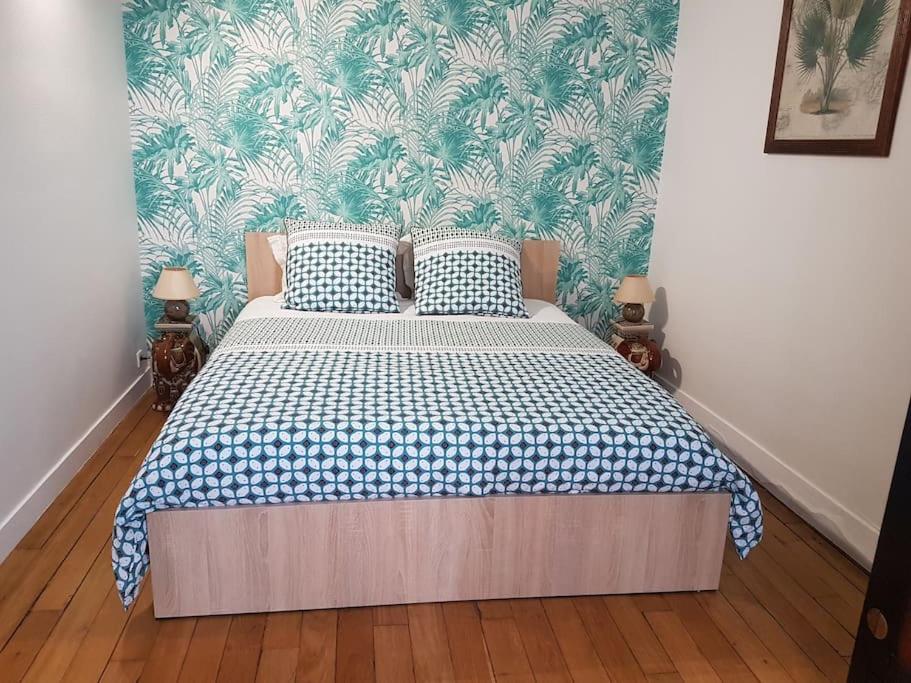 een slaapkamer met een bed met een blauwe en witte deken bij Paris Esprit loft, lumineux in Aubervilliers