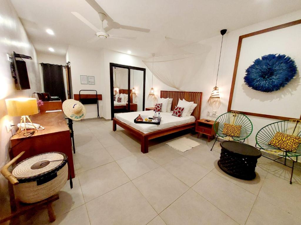 uma ampla sala de estar com uma cama e cadeiras em L'Hédone, hôtel de charme em Ouagadougou