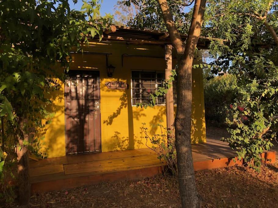 una pequeña casa amarilla con un árbol delante en Hermoso lugar de descanso en Santa Ana a una cuadra de la playa, en Balneario Argentino