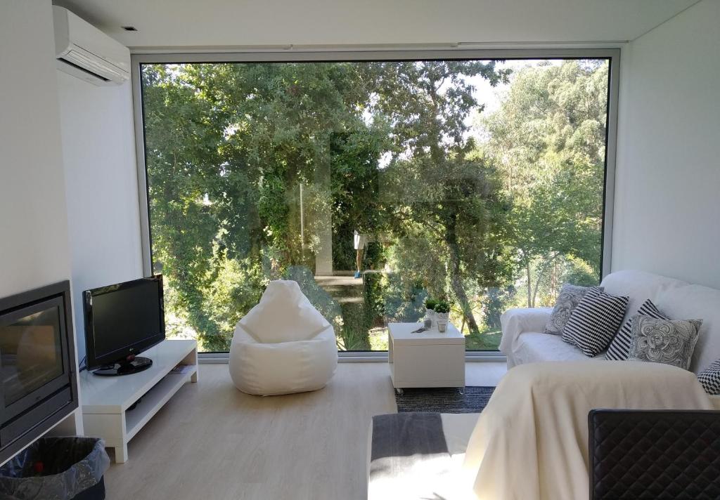 een woonkamer met een groot raam en een bank bij Ednas Place - Tranquilidade e Natureza in Caminha