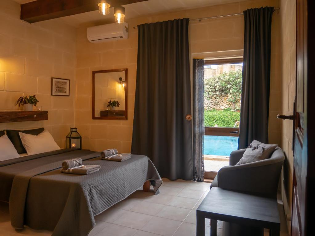 a bedroom with a bed and a chair and a window at IL Gnejna II in Xagħra