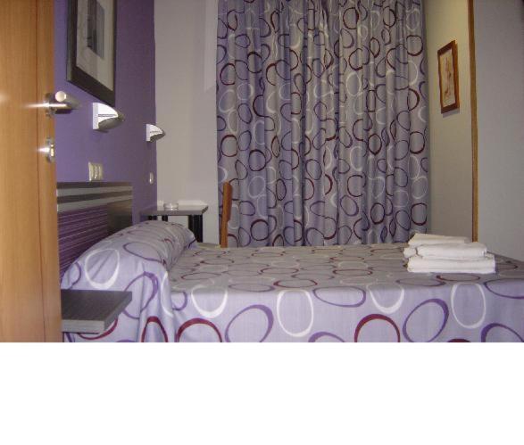 a bedroom with a purple bed and a curtain at Hostal Rica Posada in Guadalajara