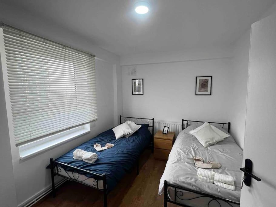 Un dormitorio con una cama y una ventana con zapatos. en Greenwich Luxury View Apartment en Londres
