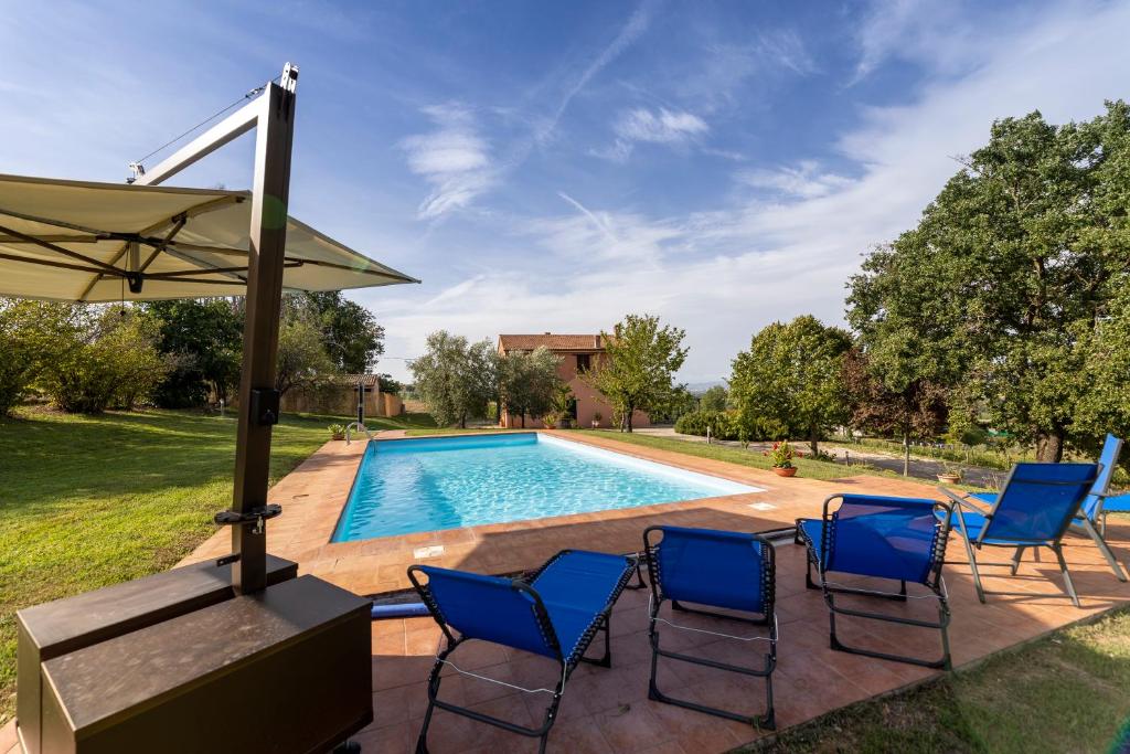 una piscina con sillas y sombrilla en Villa Collemancio la soleggiata, en Bevagna