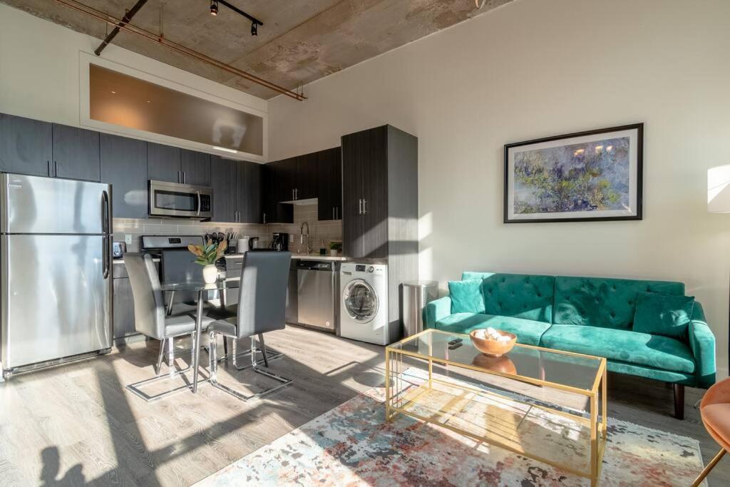 a living room with a green couch and a kitchen at McCormick Place with city view 2br/2ba - optional Parking & Gym in Chicago