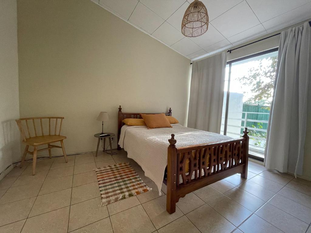 1 dormitorio con cama, ventana y silla en Casa Buda 2 Liberia cerca del aeropuerto, en Liberia