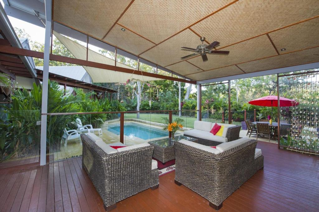 a patio with chairs and a pool and a ceiling fan at Serene Place in Nelly Bay