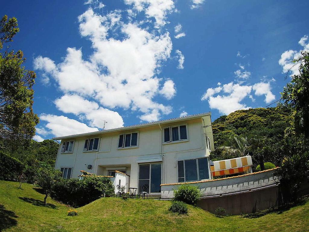 a white house on top of a green field at Hillside Inn Sirocco in Tateyama